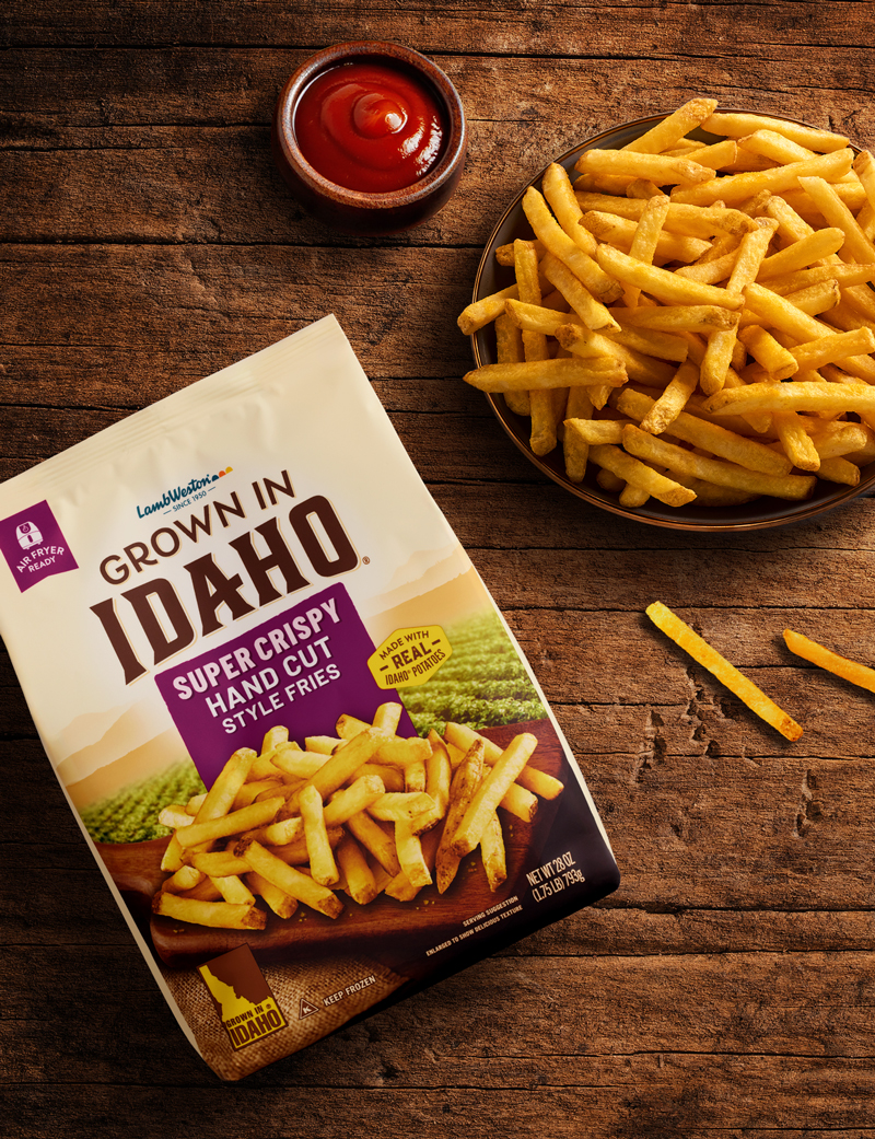 Plate of hand cut fries on wooden table.