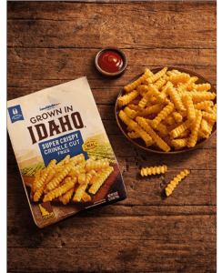 Plate of crinkle cut fries on wooden table.