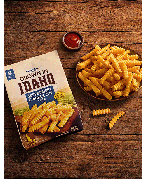 Plate of crinkle cut fries on wooden table.