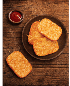 Plate of hash brown patties on wooden table.