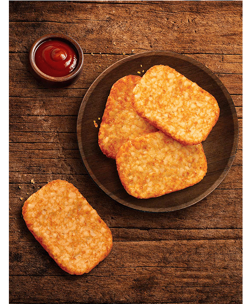 Plate of hash brown patties on wooden table.