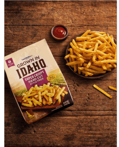 Plate of hand cut fries on wooden table.
