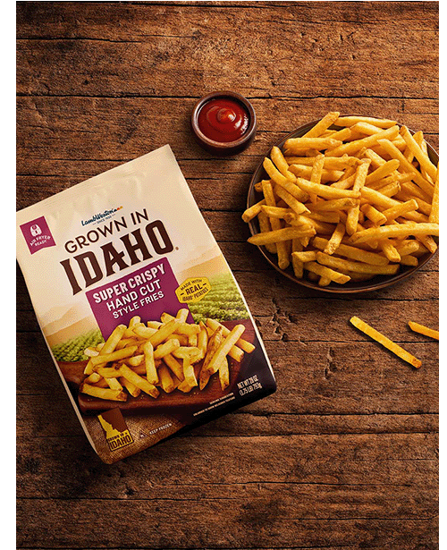 Plate of hand cut fries on wooden table.