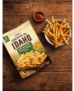 Plate of shoestring fries on wooden table.