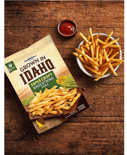 Plate of shoestring fries on wooden table.