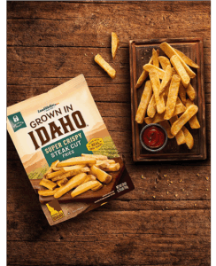 Plate of steak cut fries on wooden table.