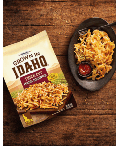 Plate of thick cut hash browns on wooden table.