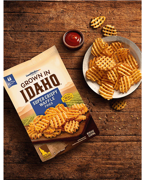 Plate of waffle cut fries on wooden table.